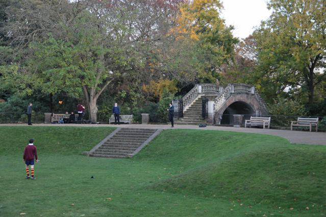 Beautiful historic house garden with an old stone bridge, walled gardens, manicured hedges, a circular pond and an ornate fountain