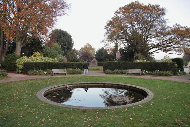 Beautiful historic house garden with an old stone bridge, walled gardens, manicured hedges, a circular pond and an ornate fountain