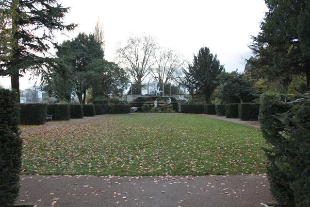 Beautiful historic house garden with an old stone bridge, walled gardens, manicured hedges, a circular pond and an ornate fountain