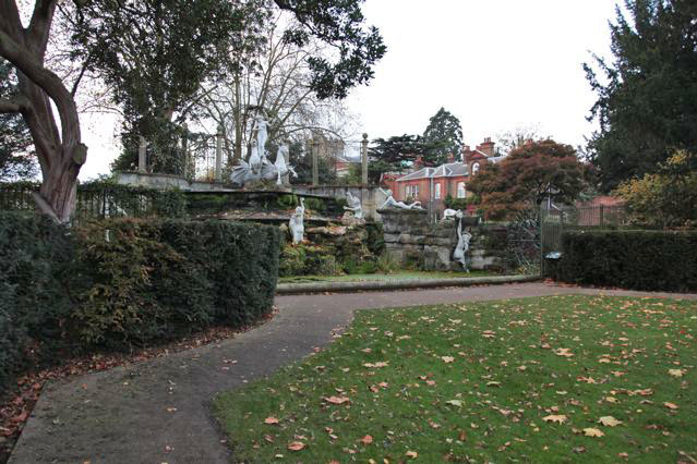 Beautiful historic house garden with an old stone bridge, walled gardens, manicured hedges, a circular pond and an ornate fountain