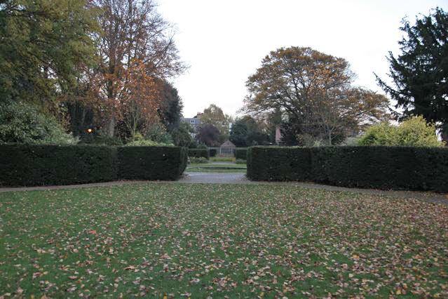 Beautiful historic house garden with an old stone bridge, walled gardens, manicured hedges, a circular pond and an ornate fountain