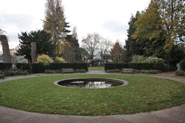 Beautiful historic house garden with an old stone bridge, walled gardens, manicured hedges, a circular pond and an ornate fountain
