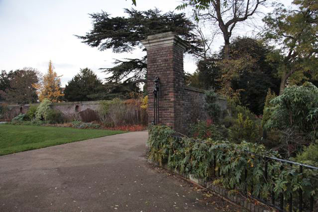 Beautiful historic house garden with an old stone bridge, walled gardens, manicured hedges, a circular pond and an ornate fountain