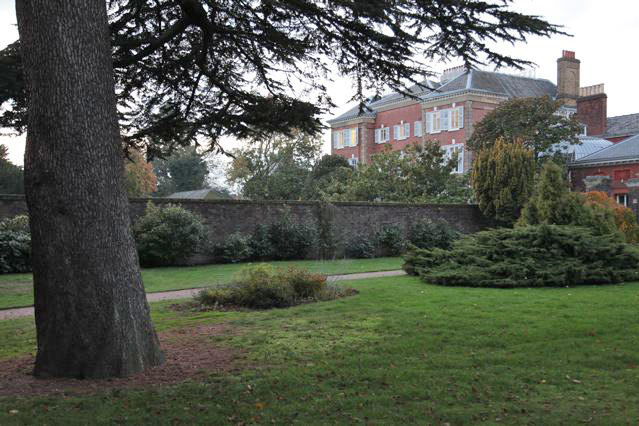 Beautiful historic house garden with an old stone bridge, walled gardens, manicured hedges, a circular pond and an ornate fountain
