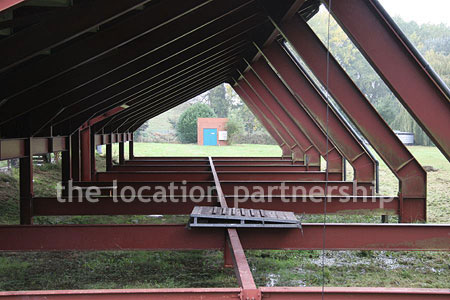 Rugby pitch with very graphic steel stand and huge straight hedge