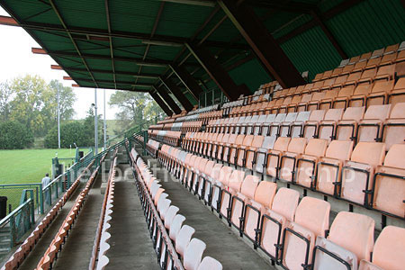 Rugby pitch with very graphic steel stand and huge straight hedge