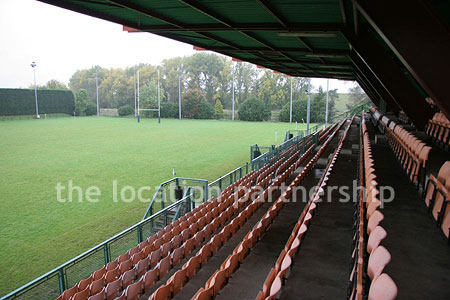 Rugby pitch with very graphic steel stand and huge straight hedge