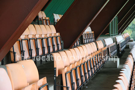 Rugby pitch with very graphic steel stand and huge straight hedge