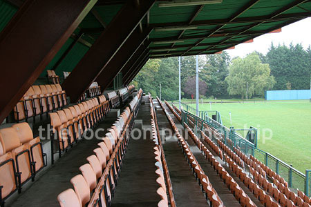 Rugby pitch with very graphic steel stand and huge straight hedge