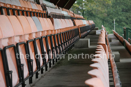 Rugby pitch with very graphic steel stand and huge straight hedge