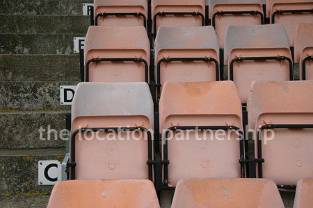 Rugby pitch with very graphic steel stand and huge straight hedge