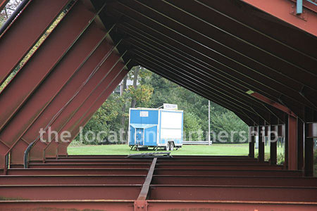 Rugby pitch with very graphic steel stand and huge straight hedge