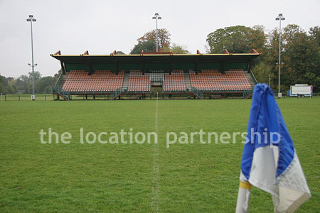 Rugby pitch with very graphic steel stand and huge straight hedge