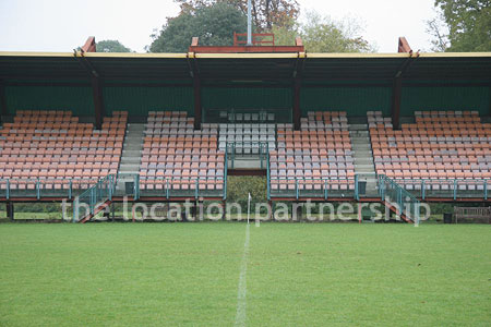 Rugby pitch with very graphic steel stand and huge straight hedge