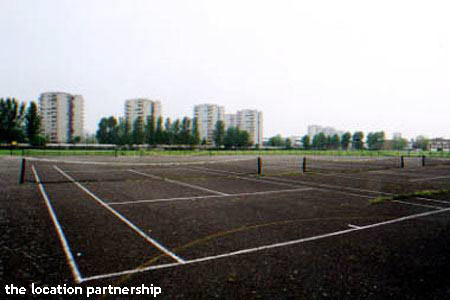 Tarmac tennis courts with graphic backdrop of tower blocks