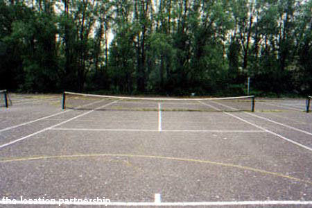 Tarmac tennis courts with graphic backdrop of tower blocks
