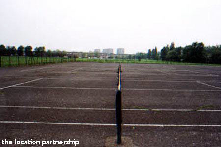 Tarmac tennis courts with graphic backdrop of tower blocks