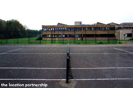 Tarmac tennis courts with graphic backdrop of tower blocks