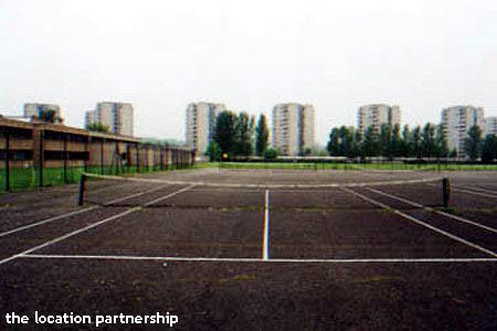 Tarmac tennis courts with graphic backdrop of tower blocks