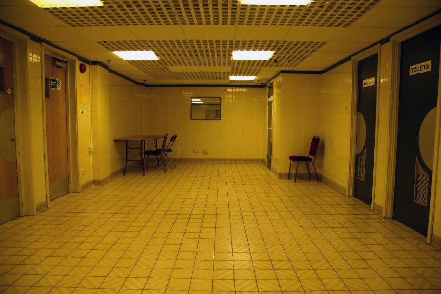 White tiled waiting area with grid pattern ceiling outside changing rooms