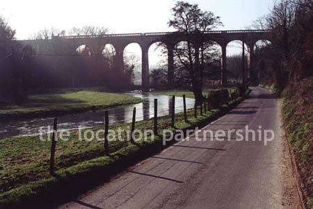 Viaduct over quiet country lane and river.``Just outside M25