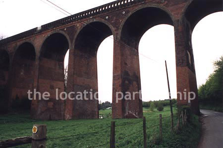 Viaduct over quiet country lane and river.``Just outside M25