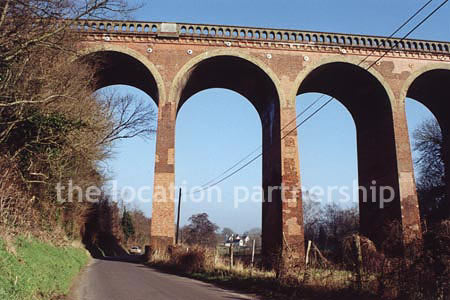 Viaduct over quiet country lane and river.``Just outside M25