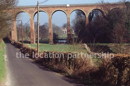 Viaduct over quiet country lane and river.``Just outside M25