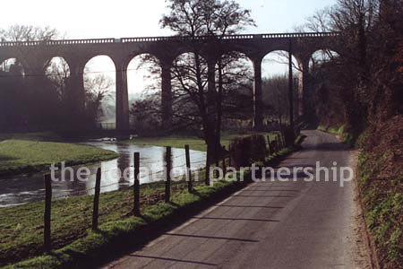 Viaduct over quiet country lane and river.``Just outside M25
