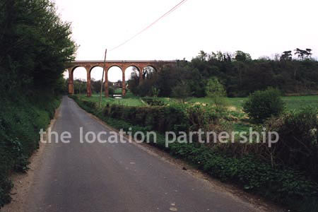 Viaduct over quiet country lane and river.``Just outside M25