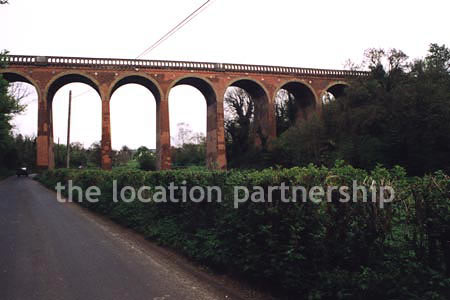 Viaduct over quiet country lane and river.``Just outside M25